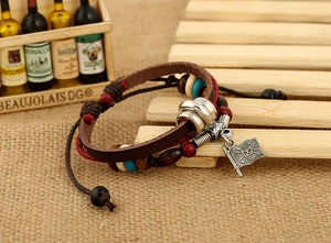 Dettaglio di un bracciale multistrato in pelle vintage con perline e ciondolo pirata