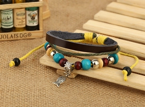 Détail d'un bracelet multicouche en cuir vintage avec un pendentif poisson argenté