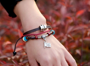 Dettaglio del bracciale multistrato in pelle con perline turchesi e ciondolo pirata