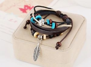 Macro shot of bohemian leather bracelet featuring wooden beads and silver feather charm