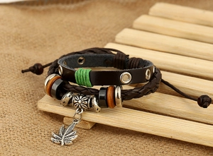 Gros plan d'un bracelet multicouche en cuir avec pendentif feuille d'érable sur bambou