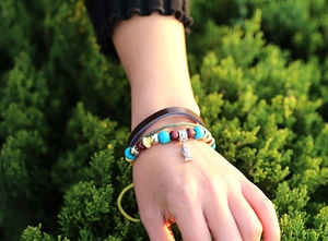 Détail d'un bracelet bohème multicouche avec pendentif poisson en argent et perles