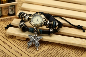 Detail of vintage leather wrap watch featuring a bronze case and butterfly charm