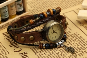 Macro detail of vintage leather wrap watch featuring bronze studs and a leaf charm