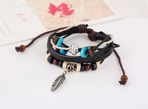 Close-up of vintage multilayer leather bracelet featuring a detailed silver feather pendant
