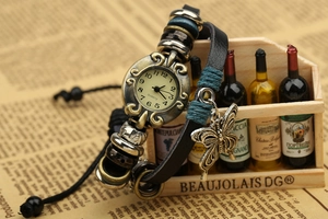 Vintage multi-layer leather wrap watch with bronze butterfly charm on newspaper background