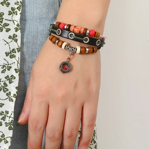Macro view of multi-layer beaded leather bracelet with vintage metal tube and ring pendant