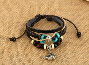 Detail of bohemian multilayer leather bracelet featuring a silver fish charm on jute background