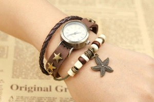 Détail d'une montre vintage en cuir multicouche avec breloque étoile de mer et pentagrammes