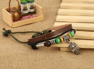 Detail of bohemian leather bracelet with multilayered braids and owl pendant