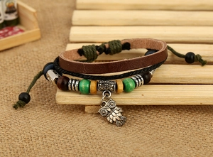 Detail of owl pendant on multilayered brown leather bracelet with wooden beads