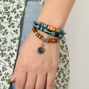 Detailed close-up of multilayer leather bracelet with wooden beads and metal pendant charms