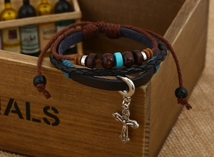 Close-up of bohemian multilayer leather bracelet with wooden beads and crucifix pendant