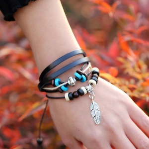 Ethnic layered leather bracelet with turquoise beads and silver feather charm on wrist
