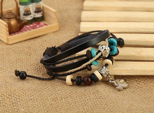 Detail of multi-layer leather bracelet with fish charm and colorful beads on burlap