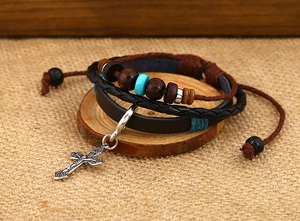 Detail of multi-layer leather bracelet with wooden beads and vintage cross charm