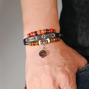 Detail showing multi-layer leather bracelet with wooden beads and ethnic metal charm
