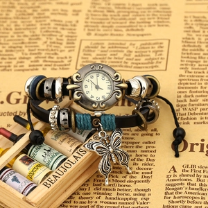 Vintage leather wrap bracelet watch with butterfly charm and bronze finish on newsprint