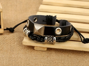 Dettaglio ravvicinato di un bracciale multistrato in pelle nera con borchie e perline d'argento