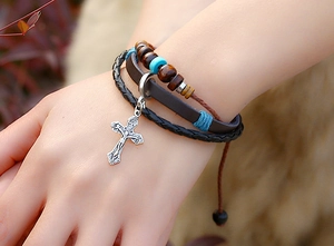 Detail of multi-layer leather bracelet featuring vintage silver cross and beaded accents
