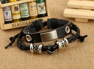 Detail of vintage black leather bracelet set featuring brushed metal plate and braided cord