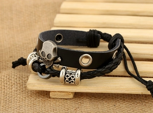 Détail d'un bracelet en cuir tressé multicouche punk avec tête de mort vintage et os