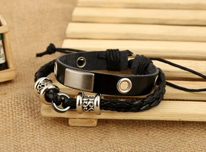 Detail of vintage black braided leather bracelet with retro silver metal beads and charms