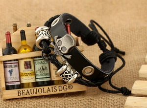 Gros plan d'un bracelet en cuir pour homme avec crâne et cordons tressés sur bois