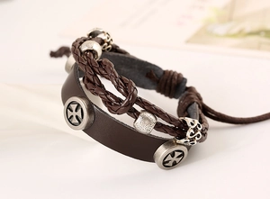 Detail of multi-layer leather bracelet with beaded cords and silver cross charm