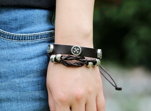 Detail of a brown multi-layer leather bracelet with cross charms and braided rope
