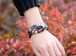 Detail of men's multi-layer leather bracelet with cross emblem and adjustable cord