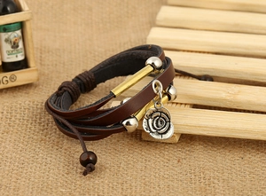 Detail of layered brown leather bracelet featuring rose charm and vintage metal beads