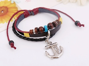 Detail of multi-layer leather bracelet with silver anchor charm and wooden beads on white base