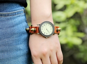 Close-up of punk style brown leather watch with brass spikes and Roman numeral dial