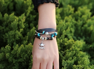 Close-up of Bohemian multilayer leather bracelet featuring a silver skull charm and turquoise beads