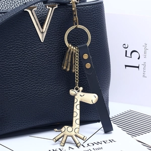 Retro brass giraffe keychain with black genuine leather strap on a stylish bag
