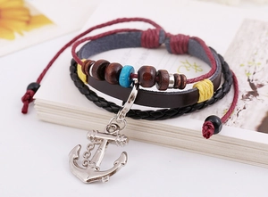 Macro shot of multi-layer leather bracelet featuring a silver anchor and wooden beads