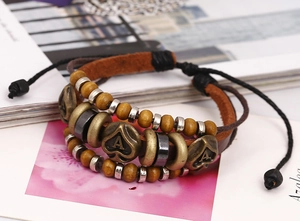 Dettaglio di bracciale multistrato in pelle con perline di legno e ciondoli in metallo