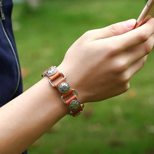 Retro brown leather bracelet with silver sun studs and metal rings worn outdoors