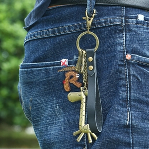 Vintage giraffe keychain with leather strap hanging on blue denim jeans belt loop