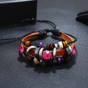 Macro detail of multi-layer leather bracelet with fuchsia rhinestones and woven beads