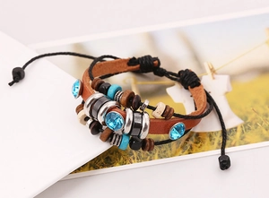 Detailed close-up of multilayer braided leather bracelet with ethnic beads and charms
