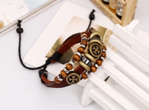 Close-up of vintage multilayer leather bracelet with wooden beads and bronze cross charm
