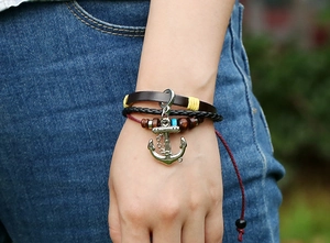 Detail of a multilayer leather bracelet with a silver anchor charm and wood beads