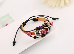 Macro detail of multi-layer leather bracelet featuring pink crystals and wooden beads