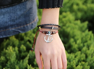 Detail of multi-layer leather bracelet with nautical anchor charm and wooden beads on wrist