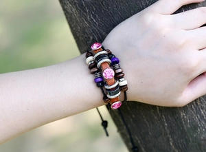 Detail of bohemian multilayer leather bracelet with pink crystals on tree bark background