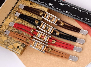 Detail of multi-layer leather bracelets in brown, black and red with metal tube accents