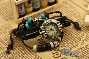 Detail of vintage bohemian quartz watch with leather straps, beads and feather pendant