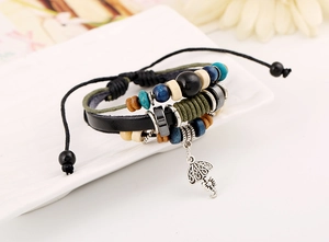 Detail of multilayer leather bracelet featuring woven cords and hollow umbrella pendant